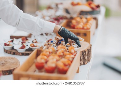 hands of a waiter prepare food for a buffet table in a restaurant. caterer arranges array of appetizers on a serving table. professional catering event with an emphasis on presentation and variety. - Powered by Shutterstock