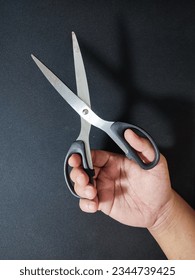 hands want to cut using scissors on a black background