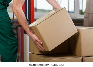 Hands Of Warehouse Worker Lifting Box, Horizontal