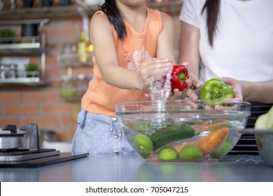 Hands washing fresh vegetables paprika red green yellow in glass bowl.