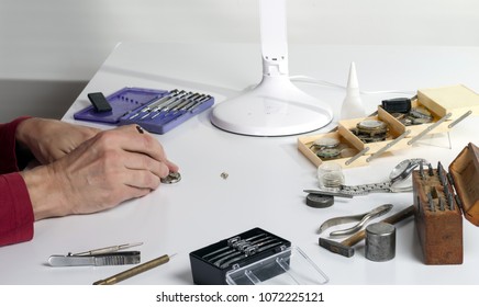 The hands of a watchmaker repairing a mechanical watch. Workplace of the clockmaker for the repair of mechanical watches. - Powered by Shutterstock