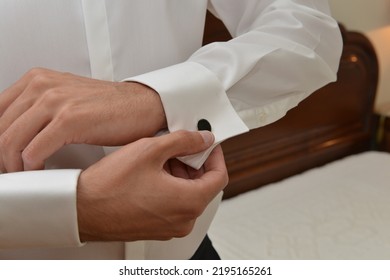 Hands Of Wedding Groom Getting Ready In The Smoking. Man Buttons Cuff Link On Cuffs Sleeves Luxury White Shirt. Close Up Of Man Hand Wears White Shirt And Cufflinks. Groom Fixes Cufflinks Concept.