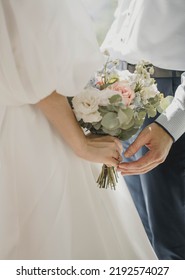 hands with wedding rings. hands of the bride and groom with wedding rings and bridal bouquet. the groom gently holds the bride's hand 