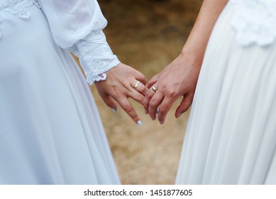 Hands With Wedding Rings Close Up. Same Sex Gay Couple Having Their Wedding, Wearing Dresses.