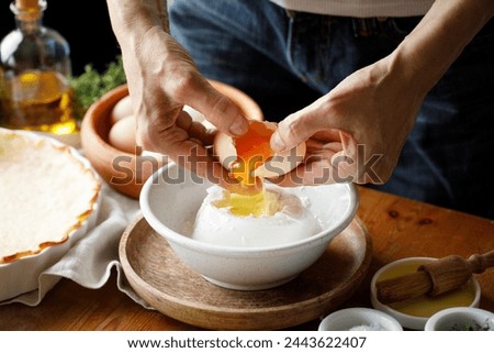 Hands while cracking an egg into the cheese mixture while preparing the pastry