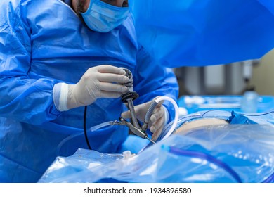 Hands in white latex gloves use special modern instruments while providing complex operation. Modern medicine. Cropped photo.