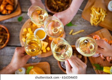 Hands with white wine toasting over served table with food. Friends Happiness Enjoying Dinning Eating Concept.