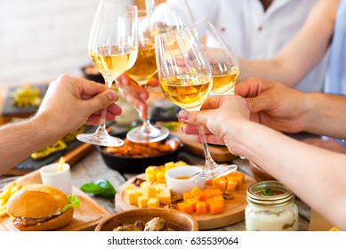 Hands With White Wine Toasting Over Served Table With Food. Friends Happiness Enjoying Dinning Eating Concept.