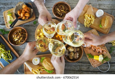 Hands With White Wine Toasting Over Served Table With Food. Friendship And Happiness Concept