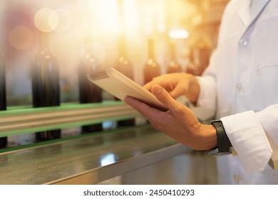 Hands of winemaker working and holding digital tablet checking line of conveyor during manufacturing in winery factory. Male winemaker worker working in winery factory - Powered by Shutterstock