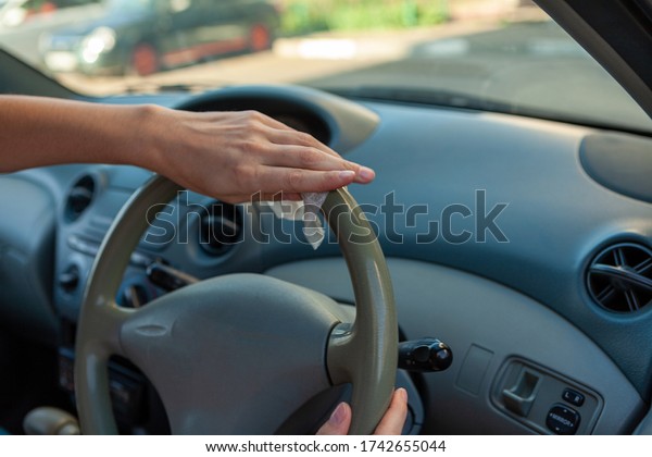 Hands wipes the steering wheel with an antibacterial\
cloth. Infection control concept. Prevent Coronavirus, COVID-19,\
flu. 