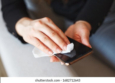 Hands Wiping Down Mobile Phone’s Surfaces Due To Corona Virus Crisis.