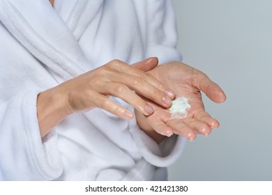 Hands Of A Woman In Bathrobe Applying Some Body Moisturiser