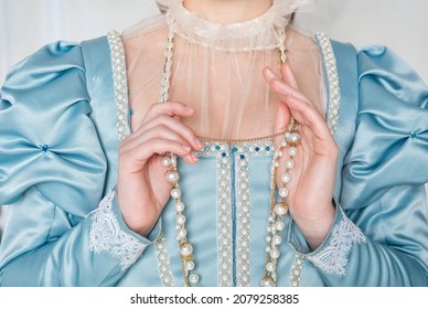 Hands of woman in beautiful blue medieval dress holding beads