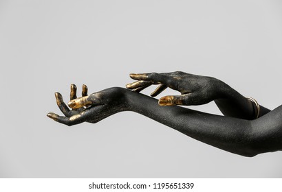 Hands Of Woman With Black And Golden Paint On Her Body Against Light Background