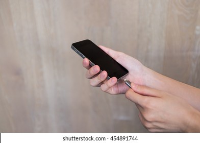 Hands of woman charging smartphone / mobile phone device with cable and adapter