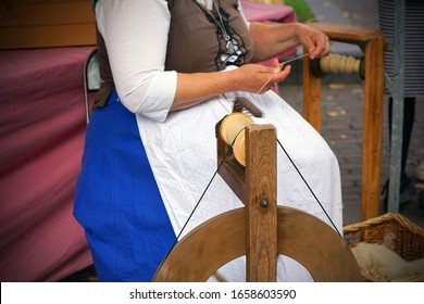 Hands of a woman demonstrating traditional wool spinning on an old spinning wheel. Craftswoman using an old spinning wheel to turn wool into yarn.  - Powered by Shutterstock