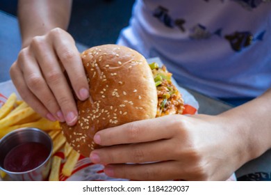 Hands Of Woman Eating Sloppy Burger.