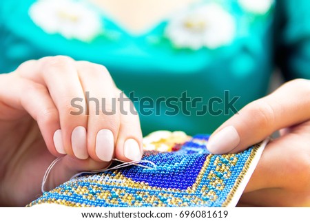 Hands of woman / female / girl in blue tradition embroidery shirt bead embroidery ornament on towel