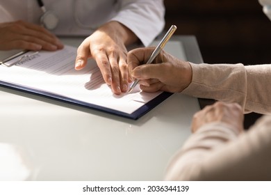 Hands of woman filling document at appointment in doctor office. Therapist, physician helping female patient to sign medical treatment contract, insurance agreement. Medic care, paperwork, Close up