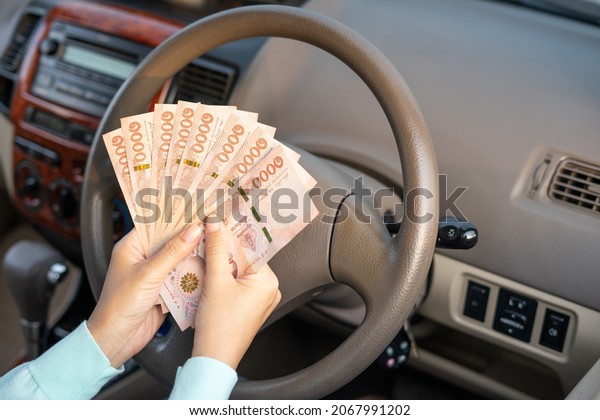 Hands woman
holding banknote in new car . Hands female of take money sitting in
her car prepare pay by installments payment a car. Loan car finance
insurance and rental
concept.