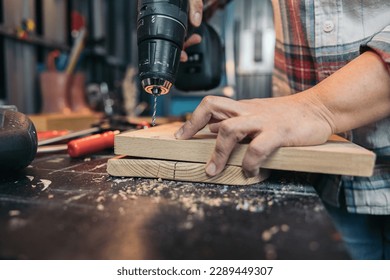 Hands of a woman holding the drill to drill a hole in a wood - Powered by Shutterstock