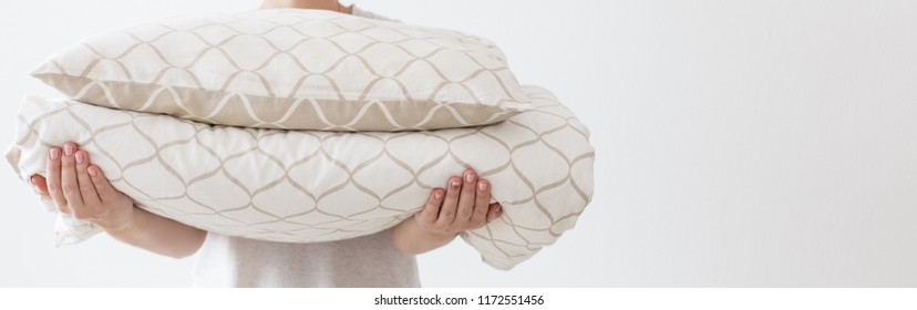 Hands of woman holding modern beige bed linen pile, white wall background in trend, minimalism clean home concept