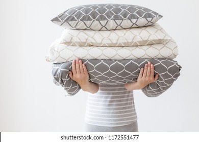 Hands of woman holding modern beige and grey bed linen pile, white wall background in trend, minimalism clean home concept