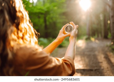 Hands of woman holding navigational compass. Female traveler holding compass in hands and navigating in nature. The concept of hiking, nature. - Powered by Shutterstock