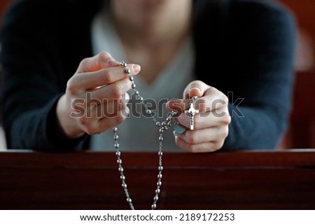 Hands of a woman holding a rosary or crucifix while praying, Christian daily devotional of a worshiper of God the Savior.  Basilica of Our Lady of La Vang.  Pilgrimage.  La Vang. Vietnam. 