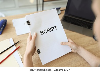 Hands of woman holding script papers for filming movie. Director assistant edits sitting at wooden table in office. Preparation for role by actress