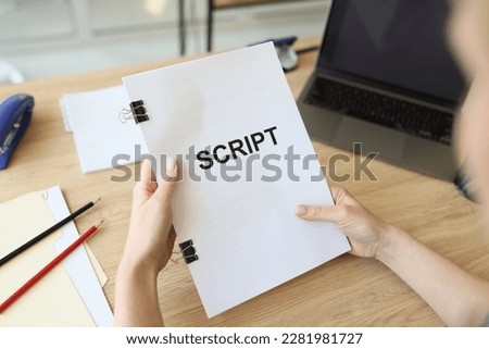 Hands of woman holding script papers for filming movie. Director assistant edits sitting at wooden table in office. Preparation for role by actress