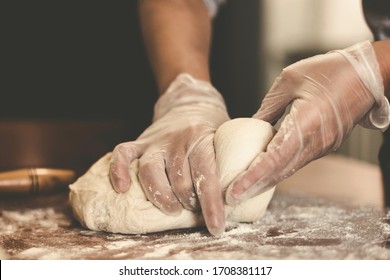 Hands of a woman making dough with plastic gloves on the table in Turkey
