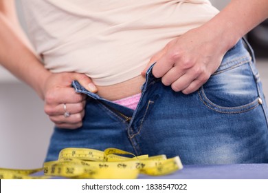 Hands of woman making efforts to button up jeans on waist - Shutterstock ID 1838547022