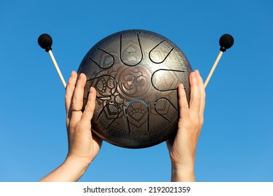 Hands Of Woman Musician Playing Steel Tongue Drum,music And Glucophone Instrument. The Inscription In Sanskrit OM