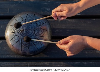 Hands Of Woman Musician Playing Steel Tongue Drum,music Andglucophone Instrument. The Inscription In Sanskrit OM