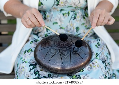 Hands Of Woman Musician Playing Steel Tongue Drum,music Andglucophone Instrument. The Inscription In Sanskrit OM