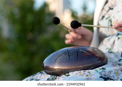 Hands Of Woman Musician Playing Steel Tongue Drum,music Andglucophone Instrument. The Inscription In Sanskrit OM