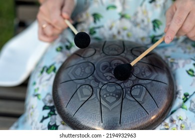 Hands Of Woman Musician Playing Steel Tongue Drum,music Andglucophone Instrument. The Inscription In Sanskrit OM