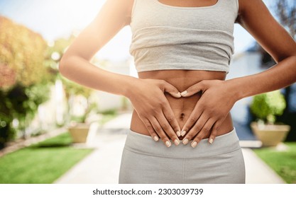 Hands of woman on stomach in park, gut health and fitness for lipo wellness for body target for balance. Gym, healthcare and tummy tuck, model with heart hand sign on belly for muscle exercise goals.