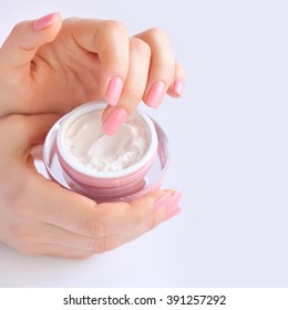 Hands of a woman with pink manicure with cream