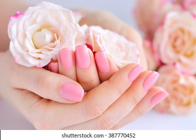 Hands of a woman with pink manicure on nails  and roses