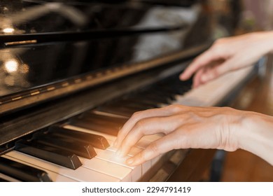 Hands of woman playing grand piano in musical school.Two hand with different level and keyboard.Blur background with light.Female pianist hands on grand piano keyboard.Playing music or song at home. - Powered by Shutterstock