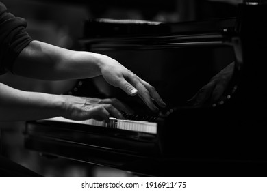 Hands of a woman playing the piano close up in black and white