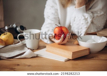 Hands of a woman at a table with a apple in her hands, close-up.