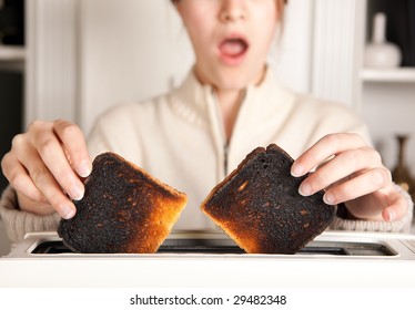 Hands Of A Woman Taking Burnt Toast Out Of A Toaster