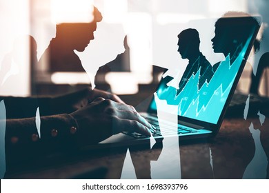 Hands Of Woman Trader Typing On Laptop With Digital Financial Graph In Blurry Office With Double Exposure Of Her Diverse Team. Concept Of Teamwork And Trading. Toned Image