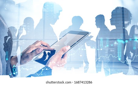 Hands of woman trader using tablet computer in blurry office with double exposure of digital graphs and night cityscape with diverse business team. Concept of stock market and teamwork. Toned image - Powered by Shutterstock