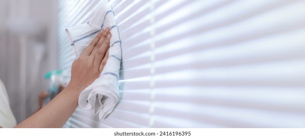 Hands of the woman uses fabric and water spray to clean the window blind - Powered by Shutterstock