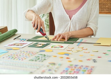 Hands of woman using sharp knife when cutting colored paper for making greeting cards for birthday - Powered by Shutterstock